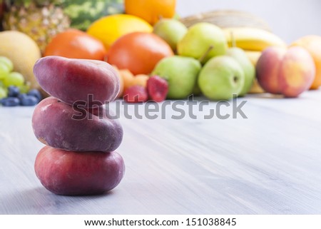 Close up photo of edible fruits - a peaches with other full colors fruits in the background on a solid  bright blue wooden table