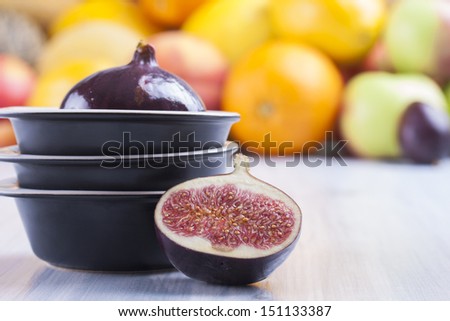 Close up photo of edible fruits - a figs with other full colors fruits in the background on a solid  bright blue wooden table