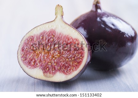 Close up photo of edible fruits - a figs with other full colors fruits in the background on a solid  bright blue wooden table