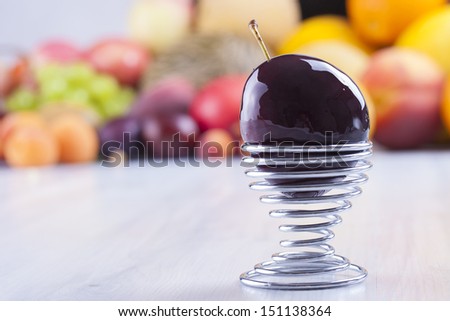 Close up photo of edible fruits - a plum with other full colors fruits in the background on a solid  bright blue wooden table