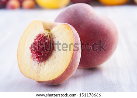 Close up photo of edible fruits - a peach with other full colors fruits in the background on a solid  bright blue wooden table
