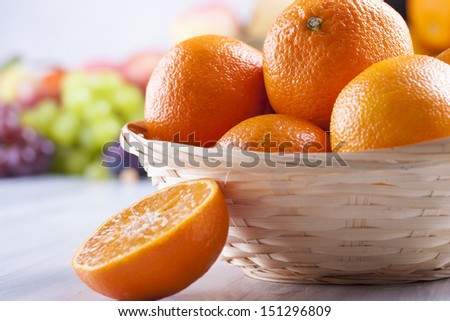 Close up photo of edible fruits - a oranges with other full colors fruits in the background on a solid  bright blue wooden table