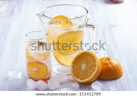 Fresh fruit and water drink with a orange slices, mint herb and ice cubes.