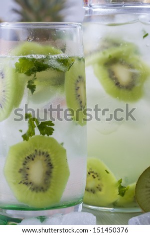 Fresh fruit and water drink with a green kiwi slices, mint herb and ice cubes.