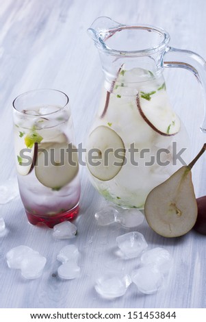 Fresh fruit and water drink with a red pears slices, mint herb and ice cubes.