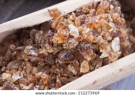Close up photo of caramelized sugar in a spatula on a dark solid wooden background.