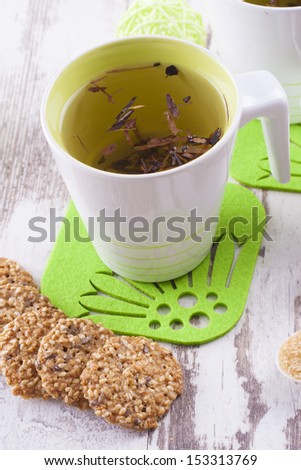 Close up photo of the herbal tea - cup of tea with a biscuits on the bright background.