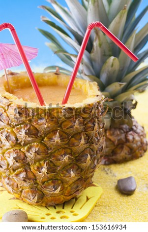 Close up photo of summer cocktail - mixed pineapple drink on a sand and blue background.