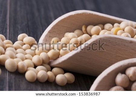 Close up photo of a raw food - yellow beans - soybeans placed on a dark wooden background.
