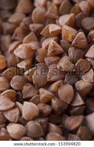 Close up photo of a eco raw food in the spoon - dark brown kasha on a dark wooden background.