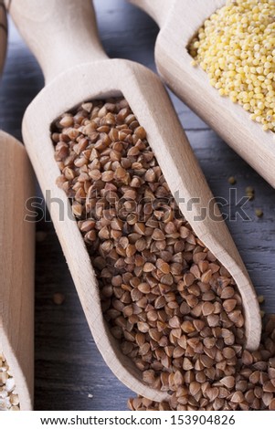 Close up photo of a eco raw food in the spoon - dark brown kasha placed on a dark wooden background.