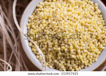 Close up photo of a eco raw food in the clay cup - yellow millet on a  wooden shavings.