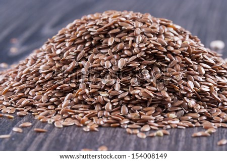 Close up photo of a raw eco food - dark brown linseeds placed on a dark wooden background.