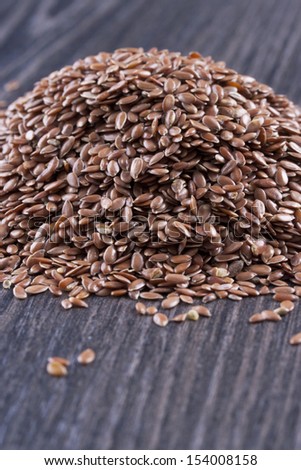 Close up photo of a raw eco food - dark brown linseeds placed on a dark wooden background.