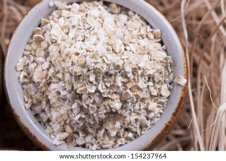 Close up photo of a cereal grain product in a clay cup - mid-brown arena bran placed on a wooden shavings.