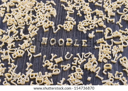 Close up photo of a letter noodles - Noodle text placed on a dark wooden background.