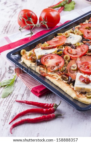 Close up photo of homemade pizza ready to baking placed on a black tray.