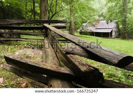 A log cabin in the woods with a split-rail fence in front.  Noah Ogle Cabin, Great Smoky Mountains National Park, near Gatlinburg, TN, USA.