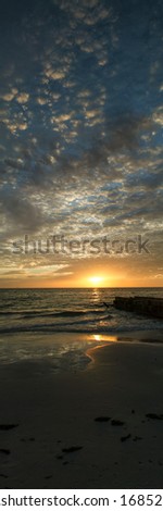A vertical panorama of a sunset on a beach.  Siesta Key, FL, USA.