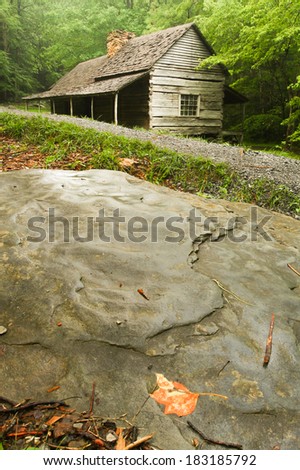 A log cabin in the woods with rocks & a gravel trail in front.  Noah Ogle Cabin, Great Smoky Mountains National Park, near Gatlinburg, TN, USA.