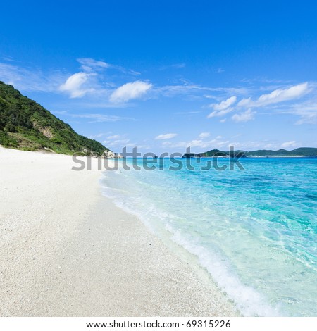 Clear water waves calmly lapping onto a white sandy tropical beach on a coral island of Okinawa, Japan