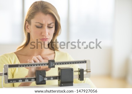 Young Caucasian woman using balance weight scale at gym