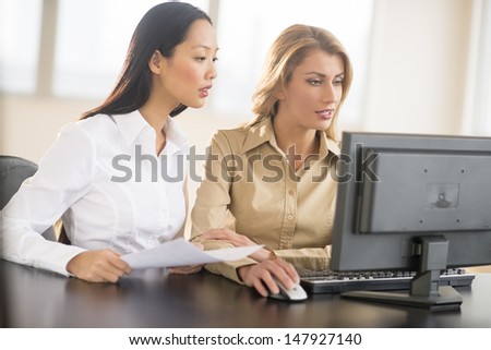 Multi-ethnic businesswomen using Desktop PC together in office