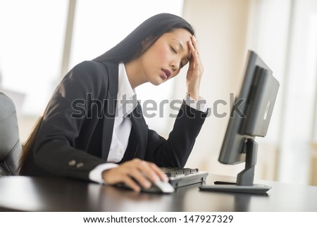 Tired mid adult businesswoman leaning while using computer at desk in office