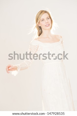 Beautiful young woman wearing evening gown looking away while standing against gray background