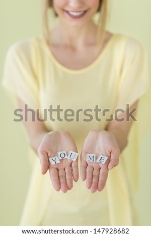 Midsection close-up of young woman holding letter blocks reading \