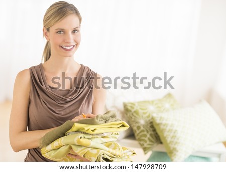 Portrait of happy female store owner holding sheets in bedding store