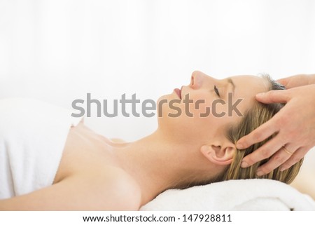 Side view close-up of beautiful young woman receiving head massage at health spa