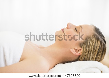 Side view close-up of beautiful young woman resting on massage table in health spa