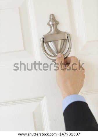 Cropped image of mature businessman\'s hand knocking door handle