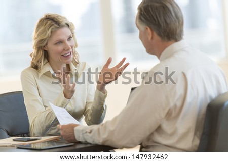 Mature Businesswoman Discussing With Male Colleague In Office