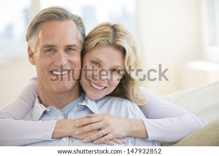 Portrait of loving mature woman embracing man from behind at home