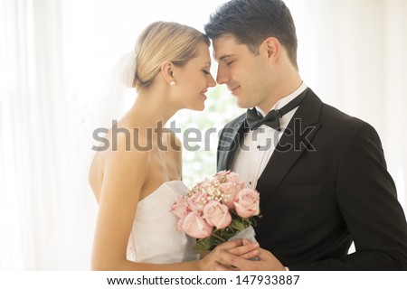 Loving young couple with flower bouquet rubbing noses
