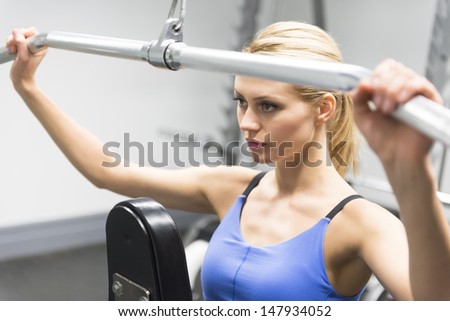 Determined young woman exercising with pulley in gym