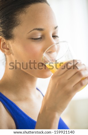 Young woman drinking glass of orange juice at gym