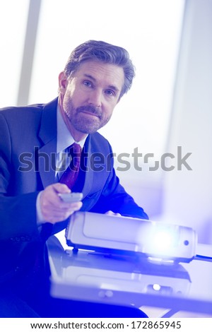 Handsome businessman working with projector at desk in office