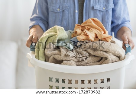 Midsection of mature man holding laundry basket at home
