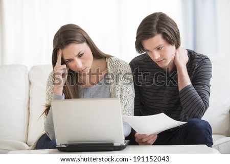 Worried young couple calculating finance on laptop at home