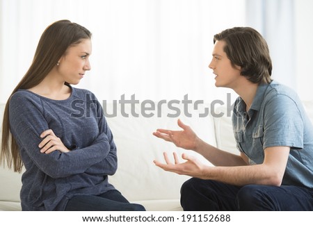 Young man explaining woman while arguing in living room