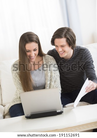Young couple calculating finances on laptop at home