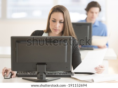 Young businesswoman using desktop PC at desk in office