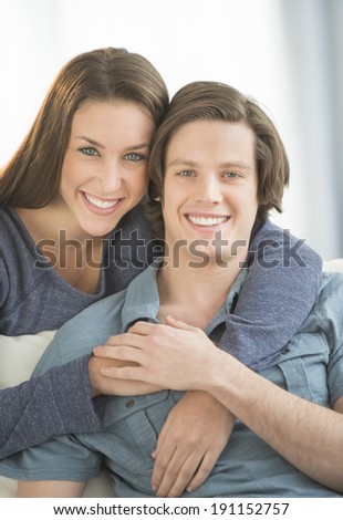 Portrait of affectionate woman embracing man from behind at home