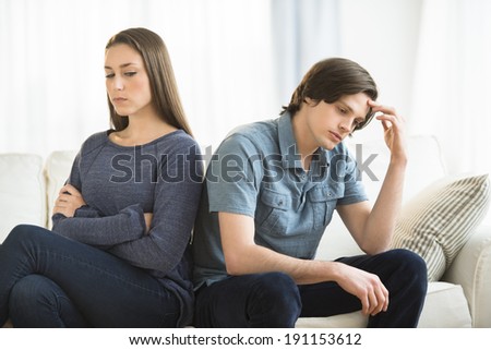 Young couple ignoring each other on sofa in living room