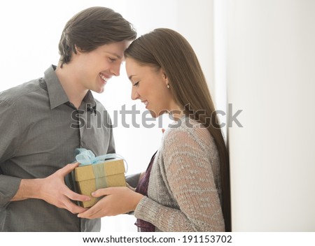 Loving young man giving birthday gift to woman at home