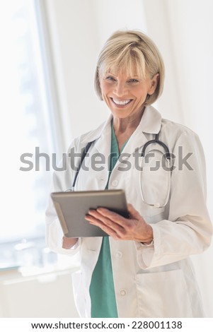 Portrait of happy mature female doctor using digital tablet in hospital