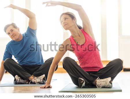 Full length of fit mature couple practicing yoga on mat at home